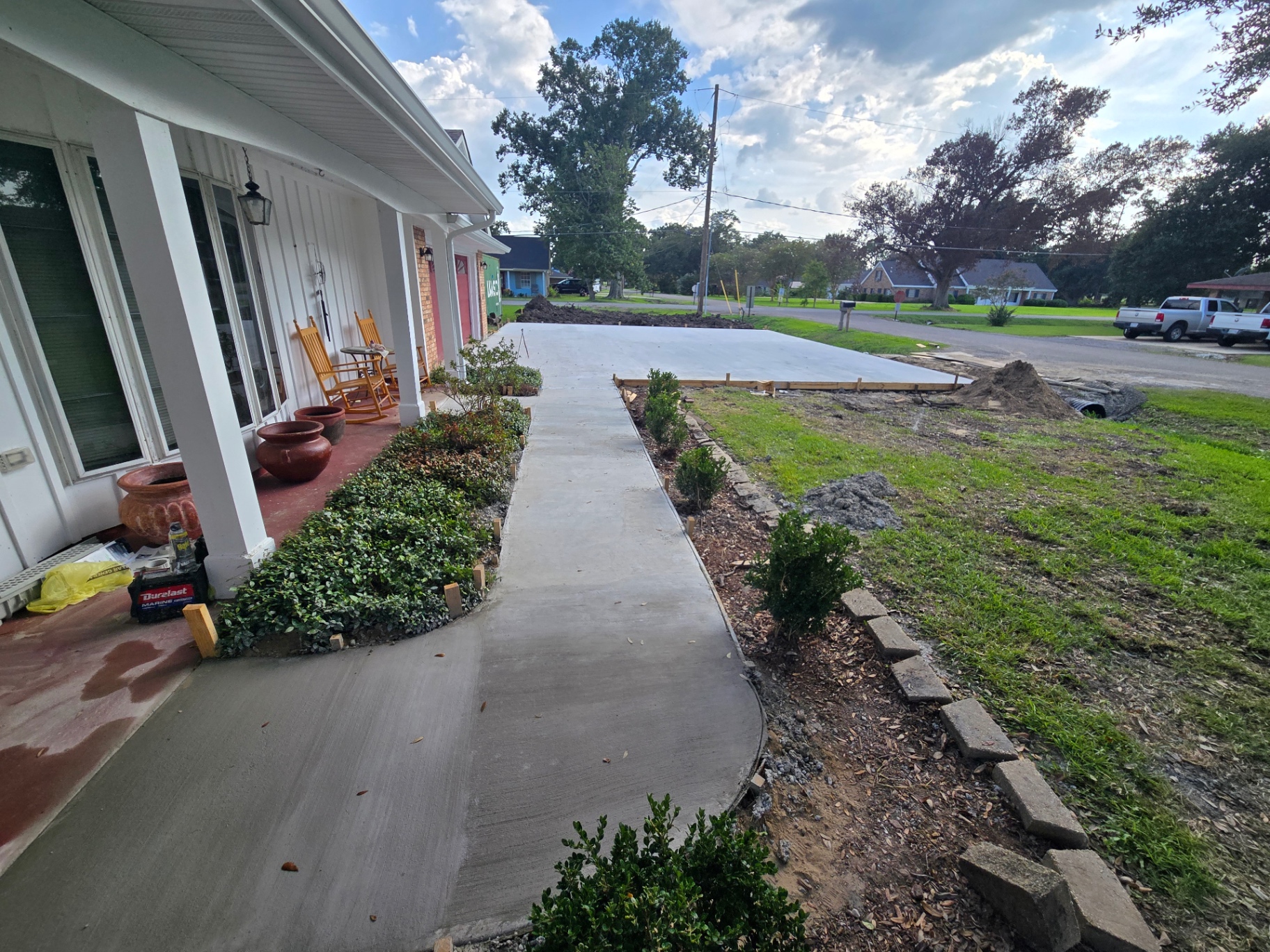 Finished curved concrete walkway leading from the front porch out to the new driveway slab