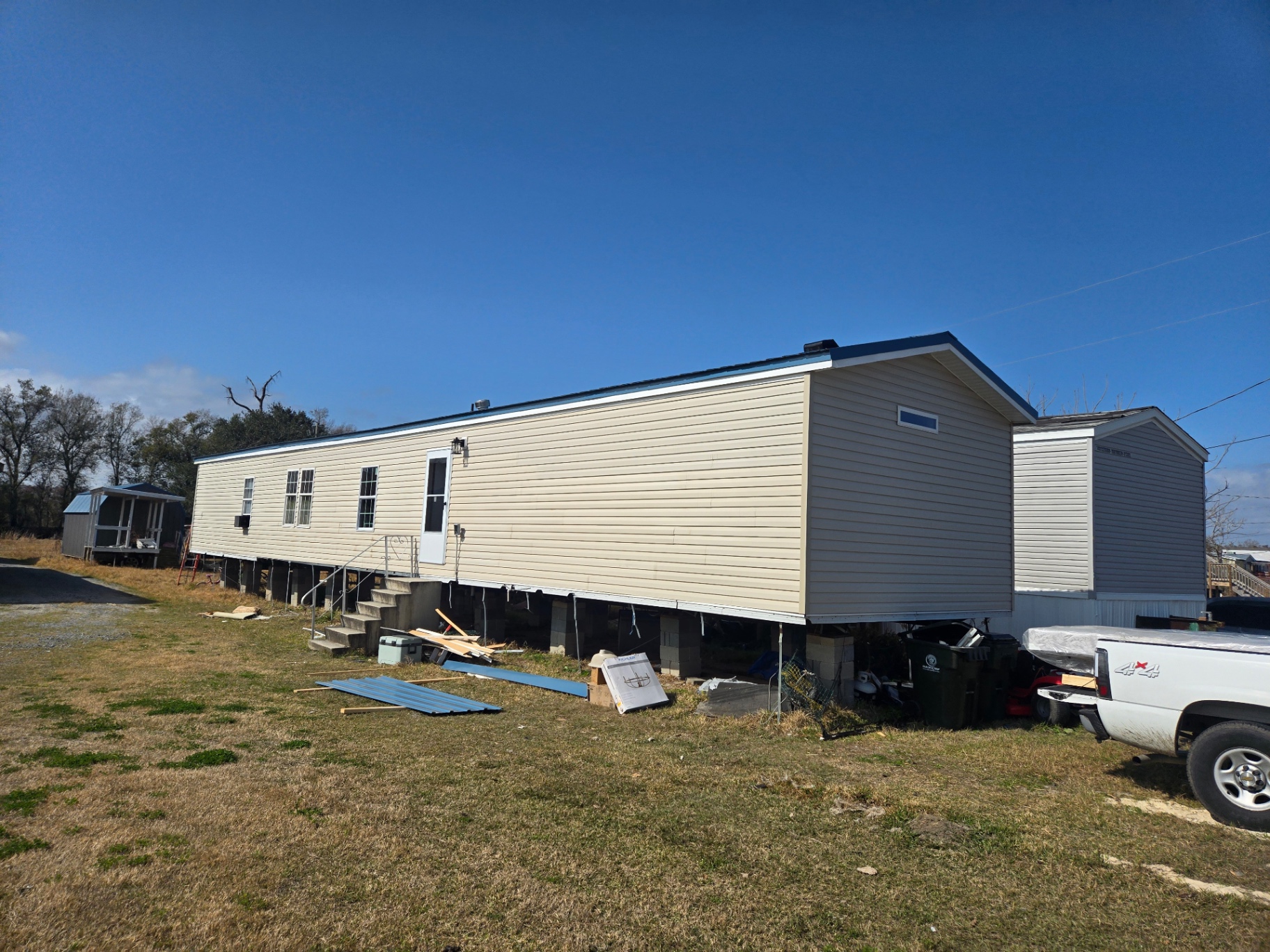 Exterior side view of the mobile home with the new blue metal roof and clean trim