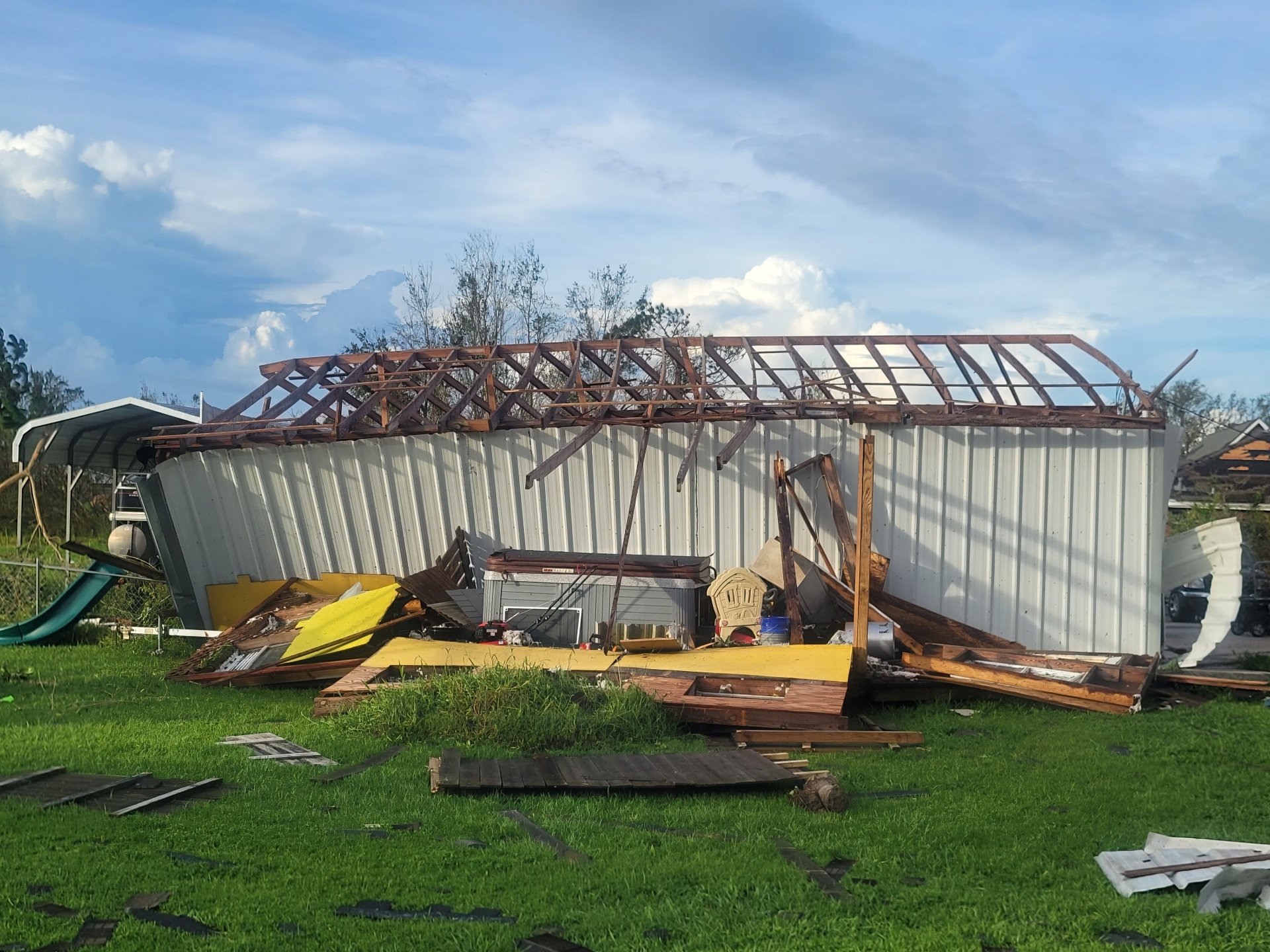 Storm-collapsed metal shop with exposed wood roof framing