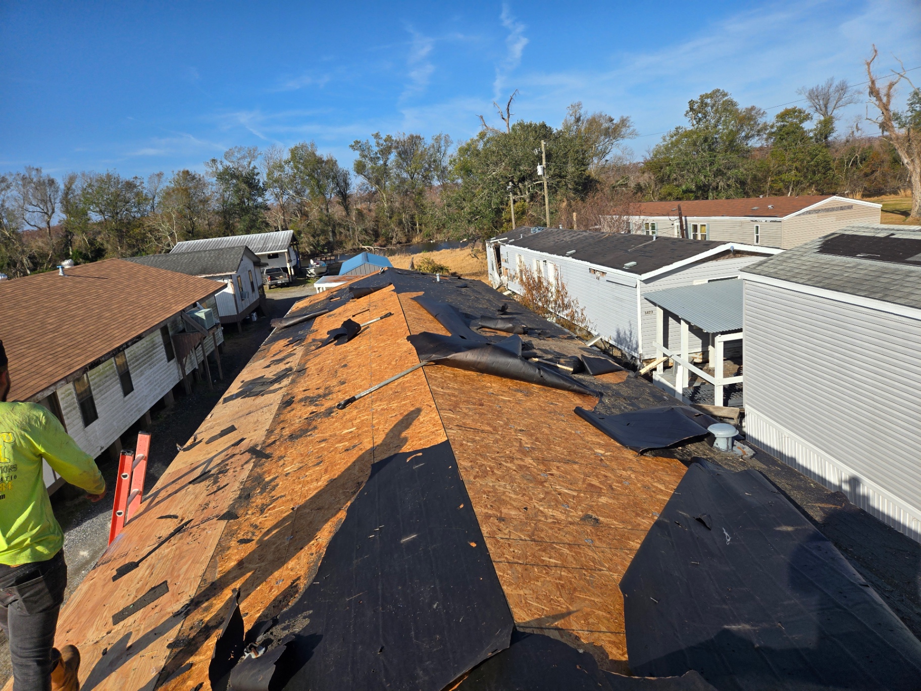 Mobile home roof fully stripped to bare decking with torn felt and shingle debris