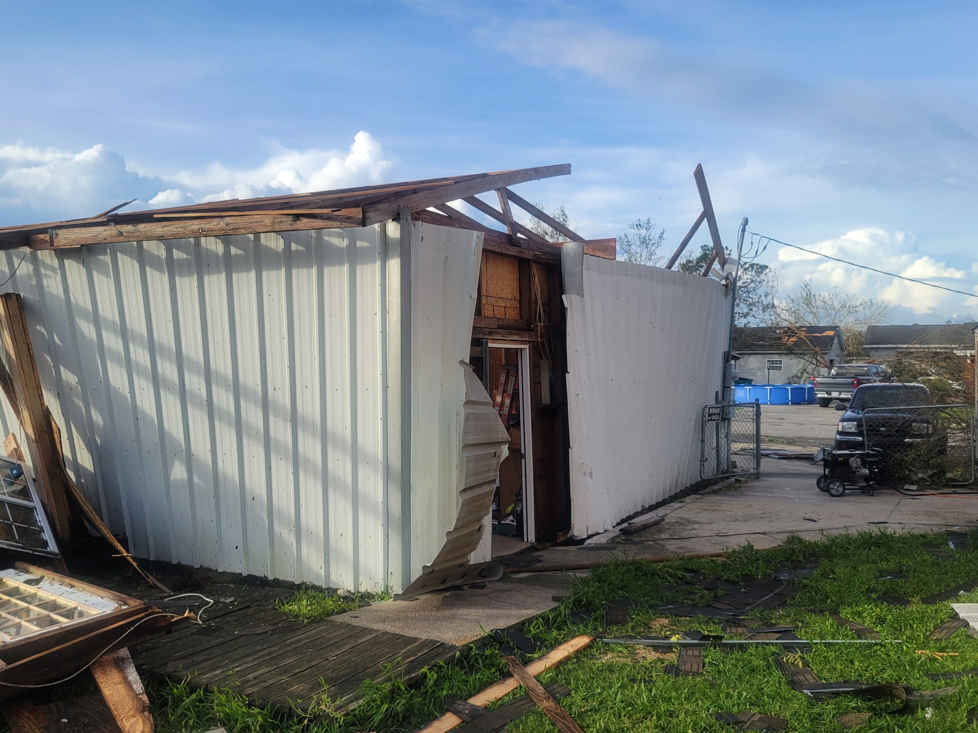 Side view of damaged metal building with torn siding