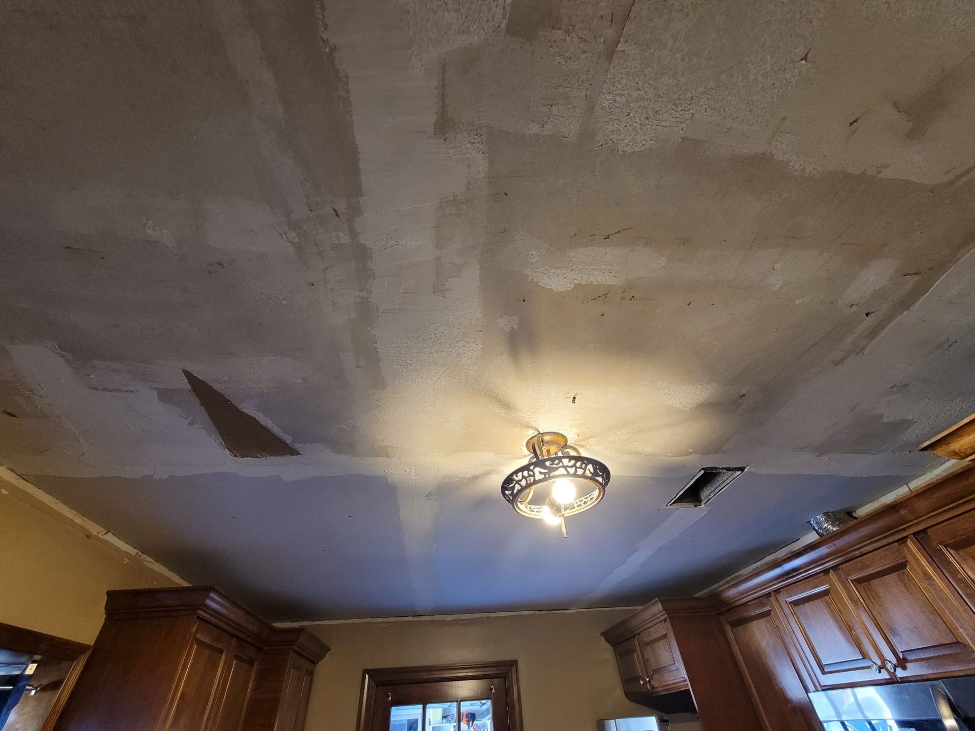 Kitchen ceiling with old popcorn texture and patched areas before smoothing