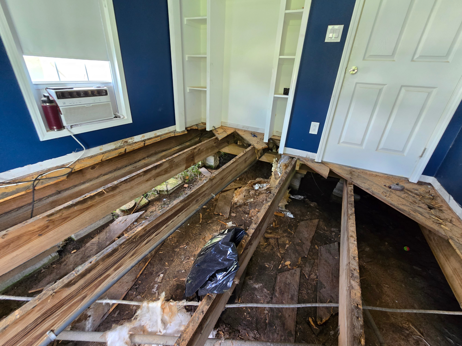 Bedroom floor opened up during repair, exposing damaged framing and subfloor below