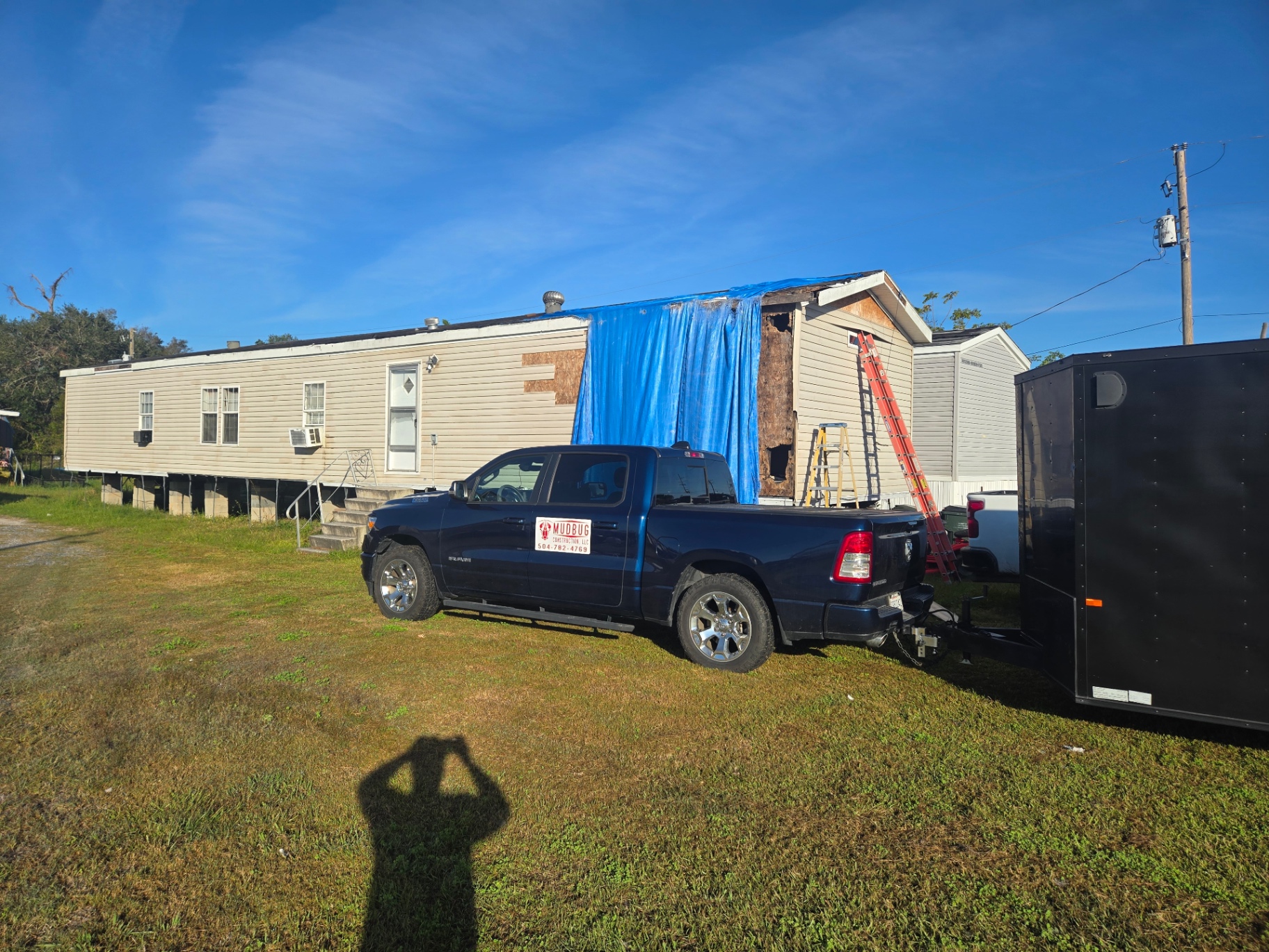 Mobile home exterior opened up for storm repair with damaged wall section exposed