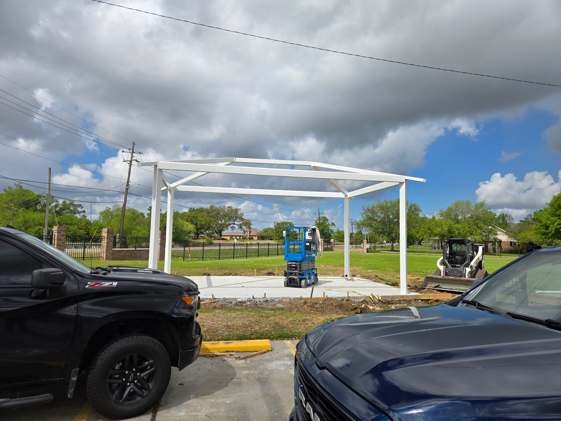 Completed white steel pavilion frame standing on the concrete pad before the roof is installed