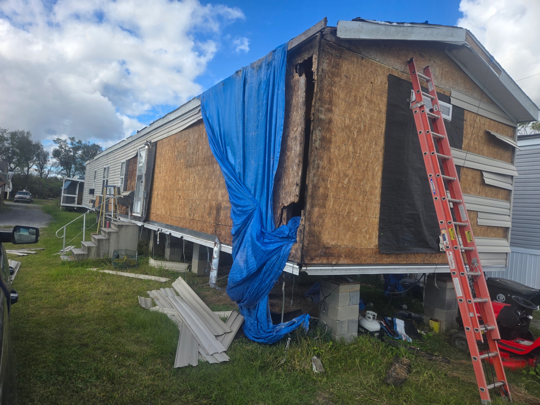 Exterior corner of the mobile home showing storm damage before repair