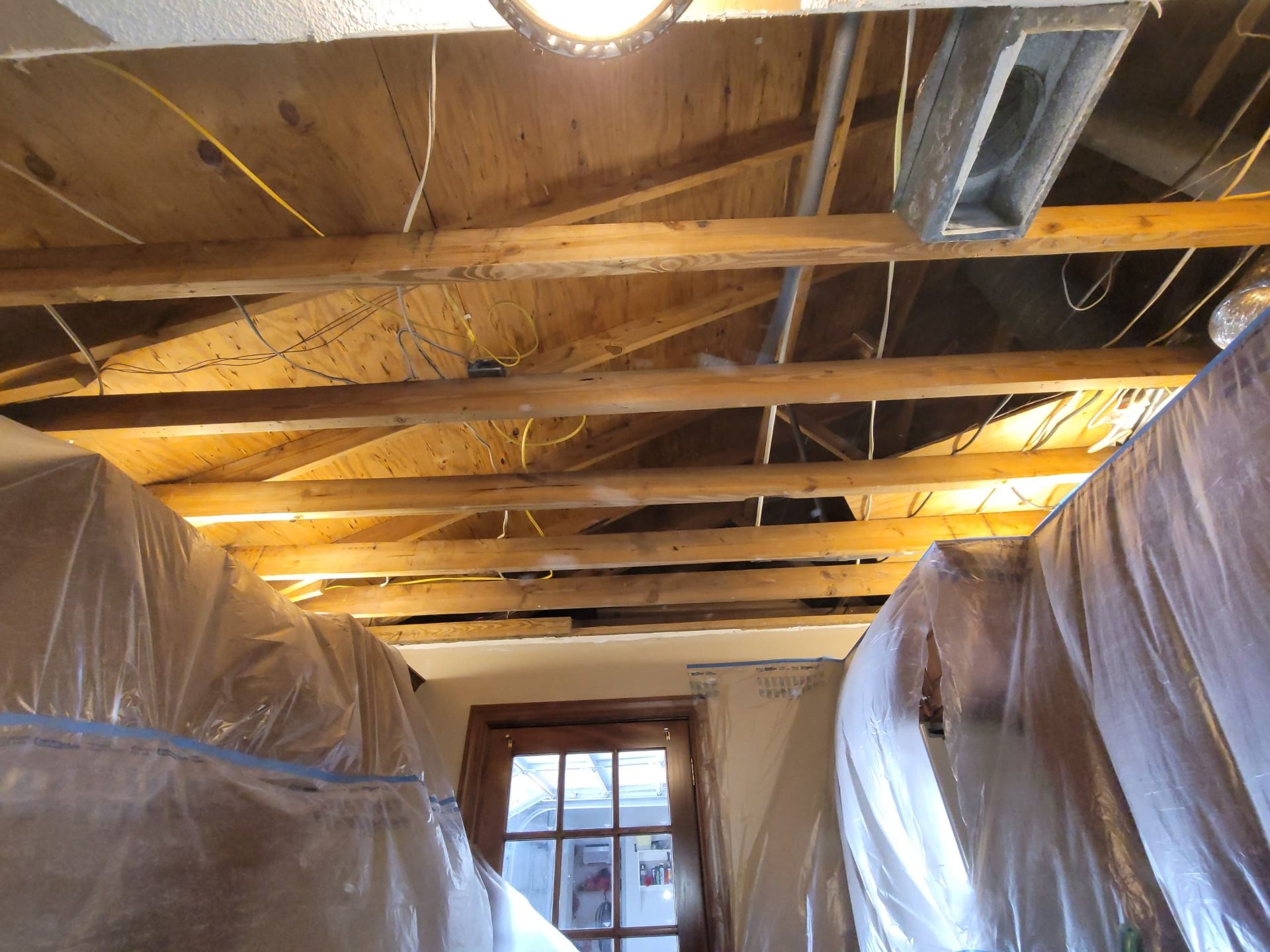 View of exposed joists and ductwork from below the opened ceiling