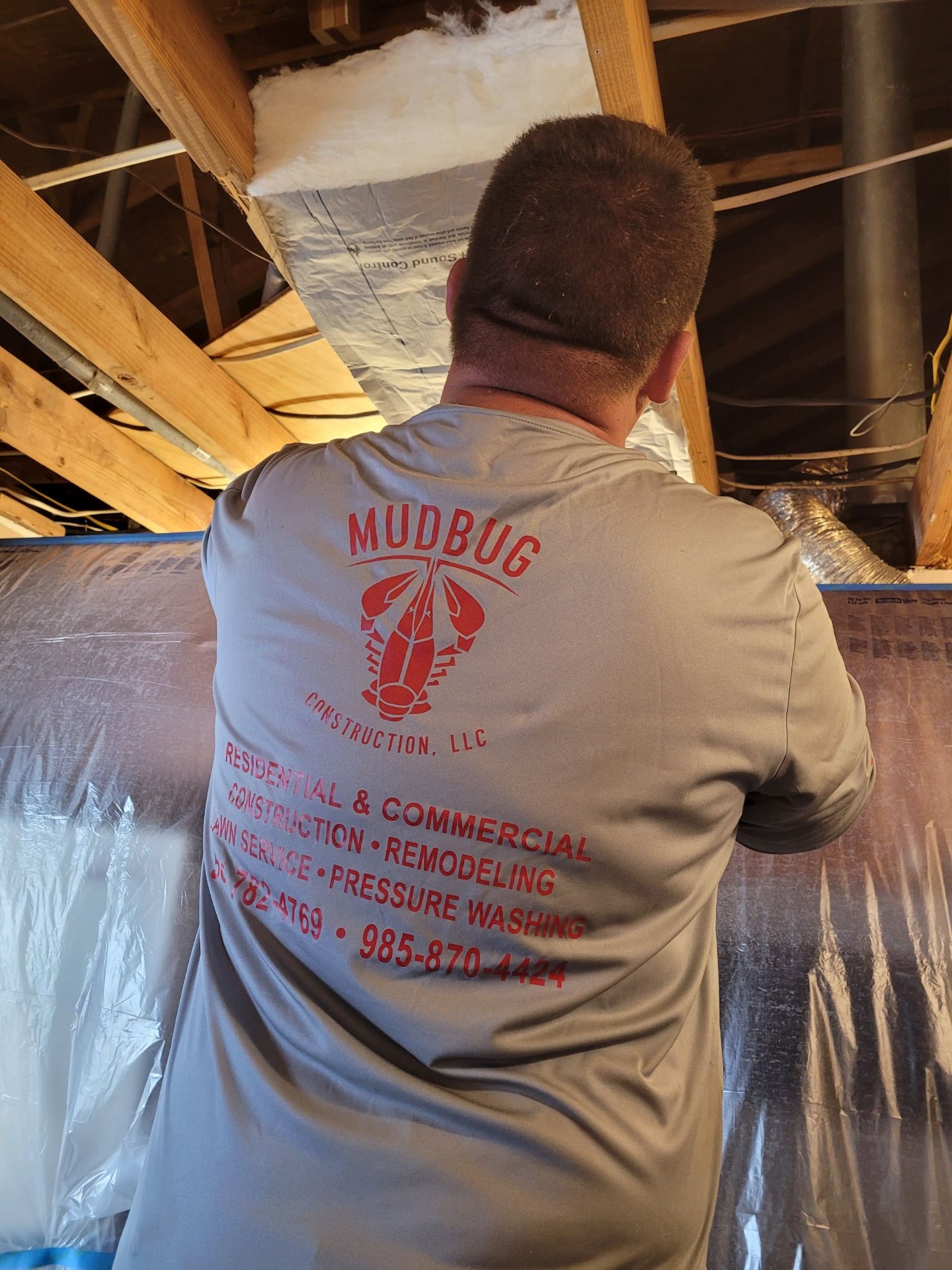 Mudbug Construction crew member replacing insulation in the attic